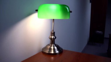 Kahverengi bir masanın üzerinde şık yeşil bir okuma lambası duruyor. Lüks apartman dekoru. Yüksek kalite 4k görüntü