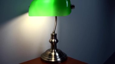 Kahverengi bir masanın üzerinde şık yeşil bir okuma lambası duruyor. Lüks apartman dekoru. Yüksek kalite 4k görüntü