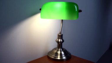 Kahverengi bir masanın üzerinde şık yeşil bir okuma lambası duruyor. Lüks apartman dekoru. Yüksek kalite 4k görüntü
