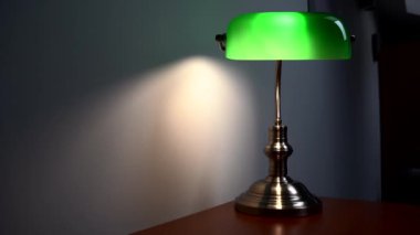 Kahverengi bir masanın üzerinde şık yeşil bir okuma lambası duruyor. Lüks apartman dekoru. Yüksek kalite 4k görüntü