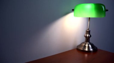 Kahverengi bir masanın üzerinde şık yeşil bir okuma lambası duruyor. Lüks apartman dekoru. Yüksek kalite 4k görüntü