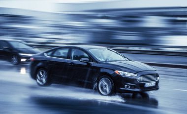 Aggravation of dosha, showers, concept. A car is moving at high speed on the street in the rain. Complicated road conditions.