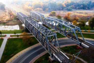 Metal double railway bridge. Freight and passenger transportation by rail. park under the bridge. Embankment of the Irpin River. A wonderful autumn landscape