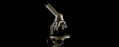 A microscope with three lenses on a black background. Concept, research science and medicine.