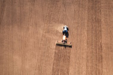 A tractor with a seeder on the field drone view, the spring season of the sowing campaign.