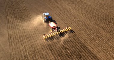 A tractor with a seeder on the field drone view, the spring season of the sowing campaign.