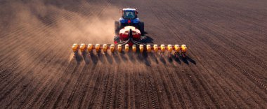 A tractor with a seeder on the field drone view, the spring season of the sowing campaign.