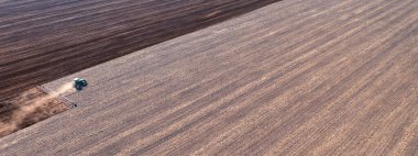 A tractor in the field cultivates the soil before the start of the sowing campaign. Drone view. Agricultural work in the field in early spring. The concept of agriculture.