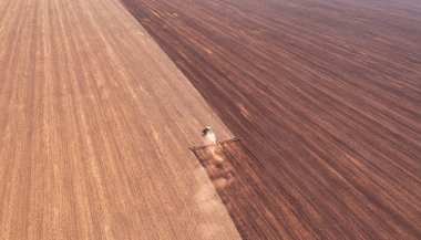 A tractor in the field cultivates the soil before the start of the sowing campaign. Drone view. Agricultural work in the field in early spring. The concept of agriculture.