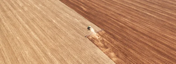 A tractor in the field cultivates the soil before the start of the sowing campaign. Drone view. Agricultural work in the field in early spring. The concept of agriculture.