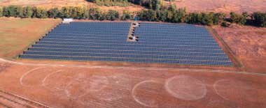 solar power station on a field with scorched grass in the foreground. The solar power station generates clean energy, highlighting the shift towards renewable energy sources and combating the effects of climate change