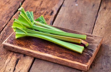 Rhubarb, taze koparılmış ve soyulmuş saplar, eski bir ahşap masaya uzanır pişirmeye hazır..