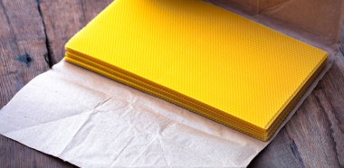 Büyüleyici bir balmumu koleksiyonu, el işi kağıtlarla paketlenmiş, eskimiş ahşap bir masada sergileniyor.