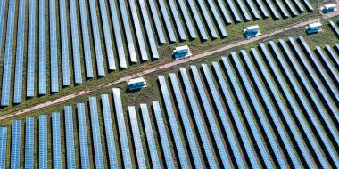 solar power station on a field with scorched grass in the foreground. The solar power station generates clean energy, highlighting the shift towards renewable energy sources and combating the effects of climate change