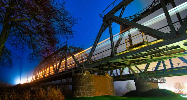Light Trail Left Passing Train Metal Bridge Set Vibrant Evening — Stock Photo, Image