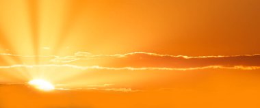 Gündüzün eşiğinde ya da gecenin arifesinde, gökyüzü yaşayan bir başyapıttır, güneşin ışıl ışıl ışıl ışınlarının altın fırça darbeleriyle süslenmiştir.