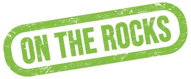 Kayalarda, yeşil dikdörtgen mühür işareti üzerinde metin.