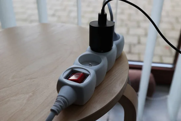 黒い充電器が付いたオフボタンの赤い白い電源ストリップの肖像画 デバイスのソケットがオフになっていて ボタンのライトがオフになっていることを示します ストック画像