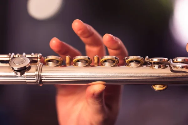 stock image A portrait of the fingers of a hand of a flutist musician releasing the pressed valves of a metal silver flute to play a note of a musical piece during a concert.