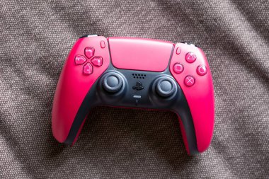 Brecht, Belçika - 14 Temmuz 2023: Resmi bir kozmik kırmızı PS5 oyun kontrolörünün üzerinde oynanmaya hazır bir tablosu. Playstation 5 çevresel aygıtında tüm simge düğmeleri var