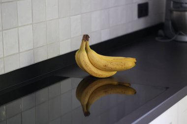 Siyah mutfak tezgahında duran kahverengi benekli sarı muzların portresi. Lezzetli enerji veren yemekler yemek için hazır ve spor etkinliğinden önce ideal..