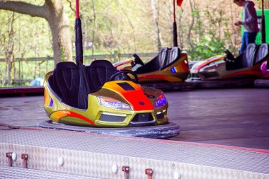 Canlı sarı ve turuncu renkli çarpışan bir araba lunapark ya da karnaval pistinde boş boş oturur, lunaparkların ve karnaval gezilerinin heyecanını yakalar..