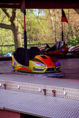 Canlı, sarı ve turuncu çarpışan bir arabanın dikey portresi lunaparkların ve lunaparkların ve karnaval gezilerinin heyecanını yansıtıyor..