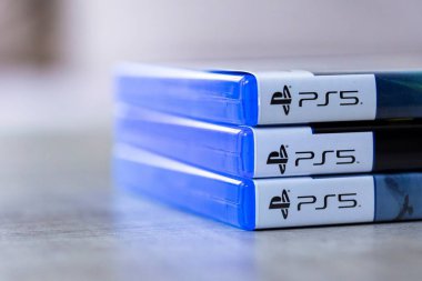Brecht, Belçika - 3 Ekim 2024: Üst üste istiflenmiş 3 Playstation 5 veya PS5 oyun çantalarının yan portresi, açılmaya ve yanlarında açık alanla oynamaya hazır.