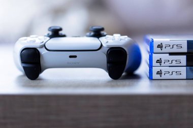 Brecht, Belçika - 3 Ekim 2024: üzerinde ps5 logosu olan oyun kasalarının yanında duran bir Playstation 5 kontrolörünün portresi. Her şey oyun konsolunda bir video oyunu oynamaya hazır..