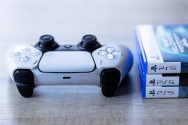 Brecht, Belçika - 3 Ekim 2024: Oyun çantalarının önünde üzerinde ps5 logosu olan bir Playstation 5 kontrolörünün portresi. Her şey oyun konsolunda bir video oyunu oynamaya hazır..