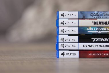 Brecht, Belçika - 18 Nisan 2025: Ahşap bir masanın üzerinde duran bir yığın Sony Playstation 5 video oyun kutusu veya kutu. PS5 oyunlarının yığını çoklu türdür.