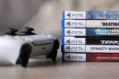Brecht, Belçika - 18 Nisan 2025: Sony Playstation 5 video oyun çantaları ya da kablosuz PS5 kontrolörünün yanındaki tahta masada duran kutular. Bir konsol oyunu oynamaya hazır.