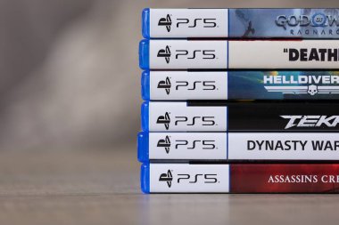 Brecht, Belçika - 18 Nisan 2025: Ahşap bir masanın üzerinde duran çoklu sony playstation 5 video oyun çantaları ya da kutular yığını. Bir konsol oyunu oynamaya hazır.