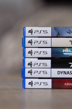 Brecht, Belçika - 18 Nisan 2025: Ahşap bir masanın üzerinde duran çoklu sony playstation 5 video oyun çantalarının veya kutuların dikey portresi. Bir konsol oyunu oynamaya hazır.