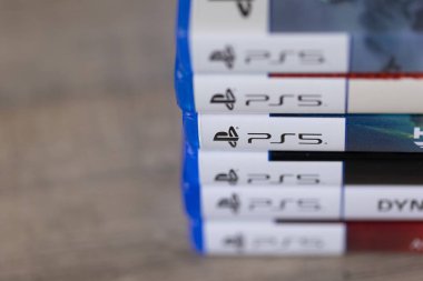 Brecht, Belçika - 18 Nisan 2025: Ahşap bir masanın üzerinde duran çoklu sony Playstation 5 oyun çantalarının veya kutuların yakın plan portresi. Bir PS5 konsol oyunu oynamaya hazır.