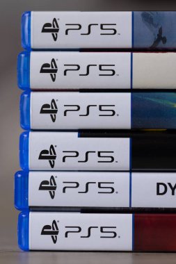 Brecht, Belçika - 18 Nisan 2025: Ahşap bir masanın üzerinde duran çoklu sony Playstation 5 oyun çantalarının veya kutuların sadece PS5 etiketlerinin yakın plan portresi. Bir konsol oyunu oynamaya hazır.