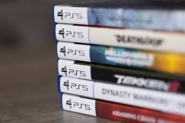 Brecht, Belçika - 18 Nisan 2025: Ahşap bir masanın üzerinde duran çoklu sony Playstation 5 oyun çantalarının veya kutuların yakın plan portresi. Bir PS5 konsolu oyunu oynamaya hazır.