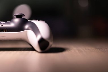 Brecht, Belçika - 18 Nisan 2025: Sony Playstation 5 'in yarısının portresi ahşap bir masanın üzerinde duran orijinal kablosuz beyaz kumanda. Bir PS5 konsol oyunu oynamaya hazır.