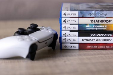 Brecht, Belçika - 18 Nisan 2025: Sony Playstation 5 video oyun çantalarının veya kutularının orijinal beyaz PS5 kablosuz kontrolörünün yanında bir portresi. Bir konsol oyunu oynamaya hazır.