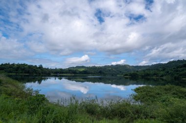 Wang Bon Rezervuarı, ağaçlar ve dağlarla çevrili, en üst kısım gökyüzü.