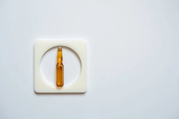 Bir ampul kahverengidir, kare bir çerçeveye sarılıdır, beyaz bir arkası vardır..