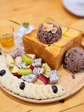 Üstüne de çikolatalı dondurma ve bolca meyve, taze muz, bir dilim çilek ve krema. Dondurma Karışık Meyve.