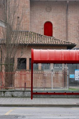 Tuğla bina arkaplanlı bir otobüs durağının kırmızı rengi.