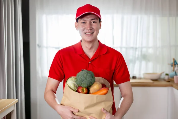 Repartidor Asiático Sonriente Uniforme Rojo Llevando Comestibles Bolsa Papel Entregando — Foto de Stock