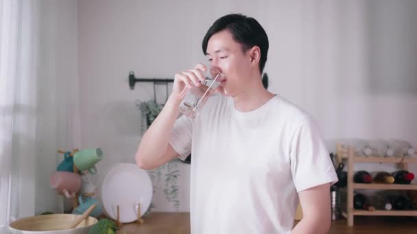 Молодий Азіат Білій Футболці Випиває Склянку Прісної Води Кухні Гідратація — стокове відео