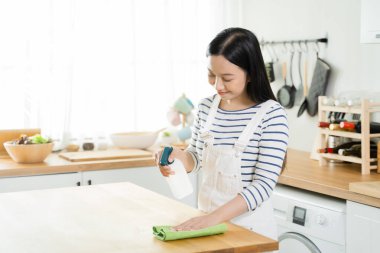 Genç Asyalı kadın masayı bezle temizliyor. Güzel temizlik işçisi temizlik ve mutfağı toparlama. Ev işleri ve ev işleri konsepti..