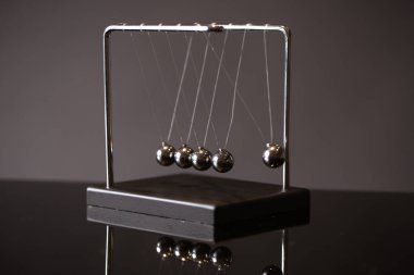 Closeup metal Newton beşiği momentum kavramı gösterimi olarak gri arka plan üzerine yerleştirilen