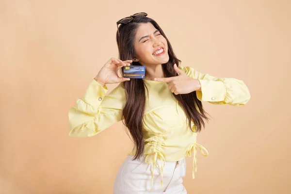 Feliz Mujer Asiática Sonriente Sosteniendo Una Tarjeta Crédito Mientras Señala —  Fotos de Stock
