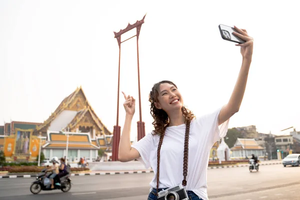 タイのバンコクに寺院の風景があるスマートフォンでビデオ通話をしている幸せなアジアの観光客 コピースペース — ストック写真