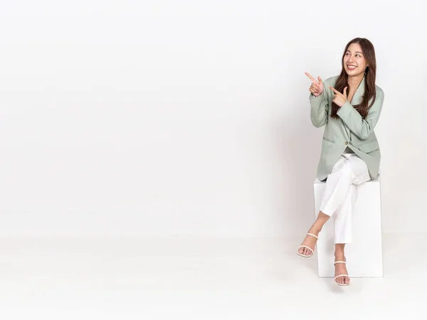 白い背景に隔離された白い箱に座ってスーツやズボンで幸せな陽気な若いアジアの実業家 広告やマーケティングのプロモーションのために使用 — ストック写真